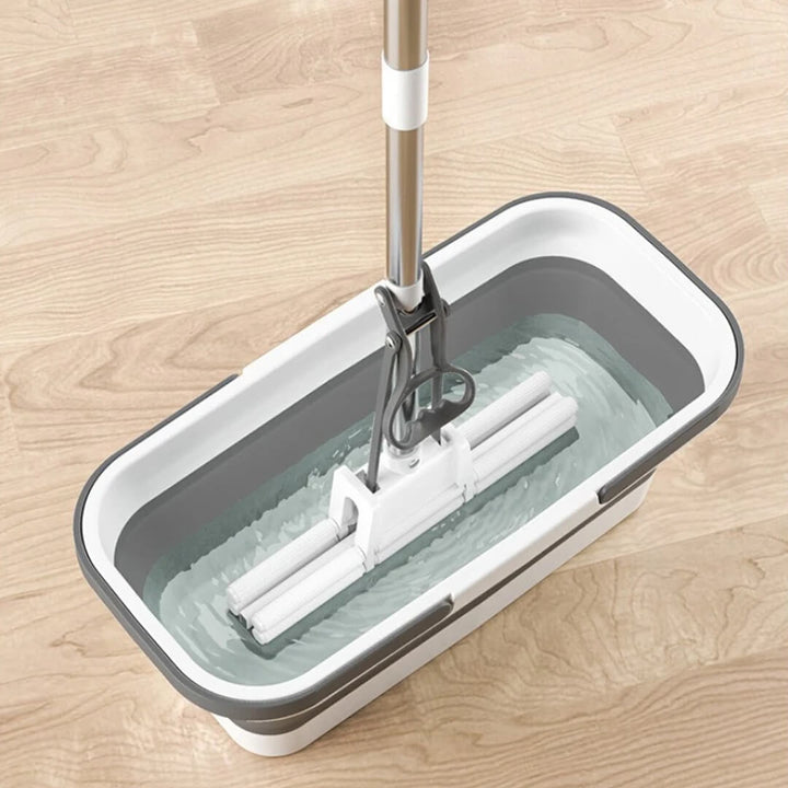 Flat mop resting inside open collapsible bucket