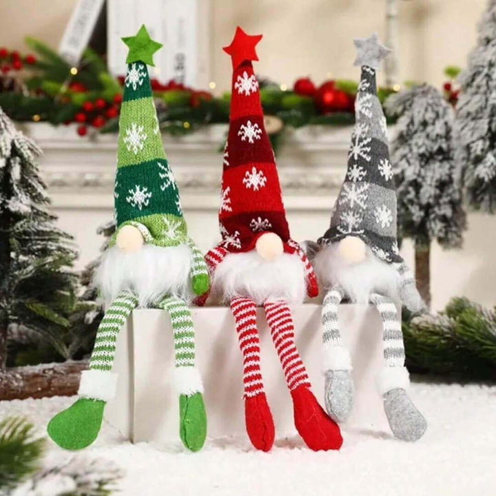 Three Christmas-themed gnomes with colorful hats and striped legs on a snowy background.