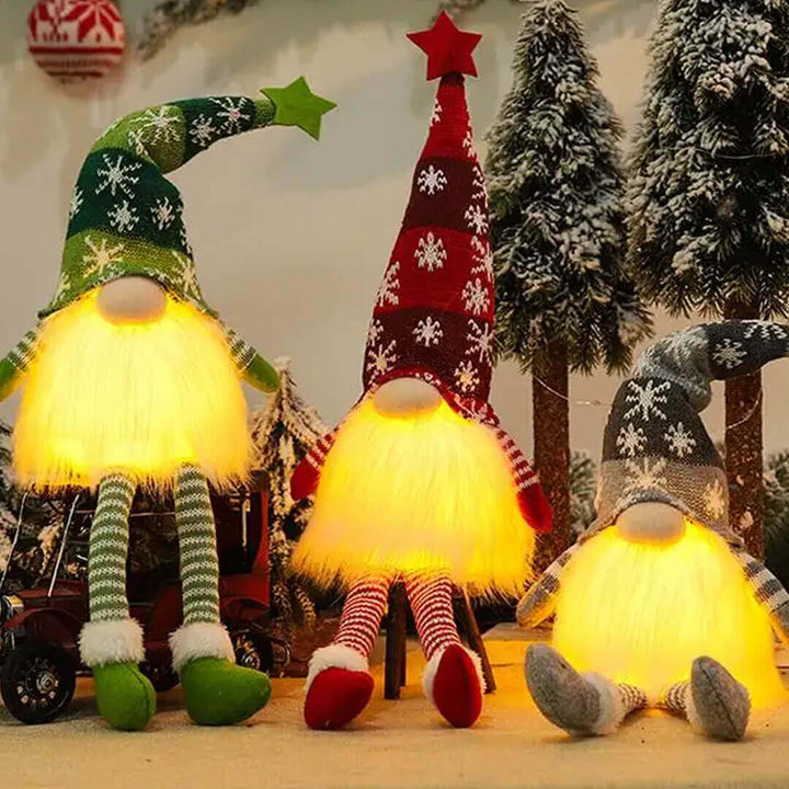 Three illuminated gnome figurines with colorful hats and striped socks in a festive setting.